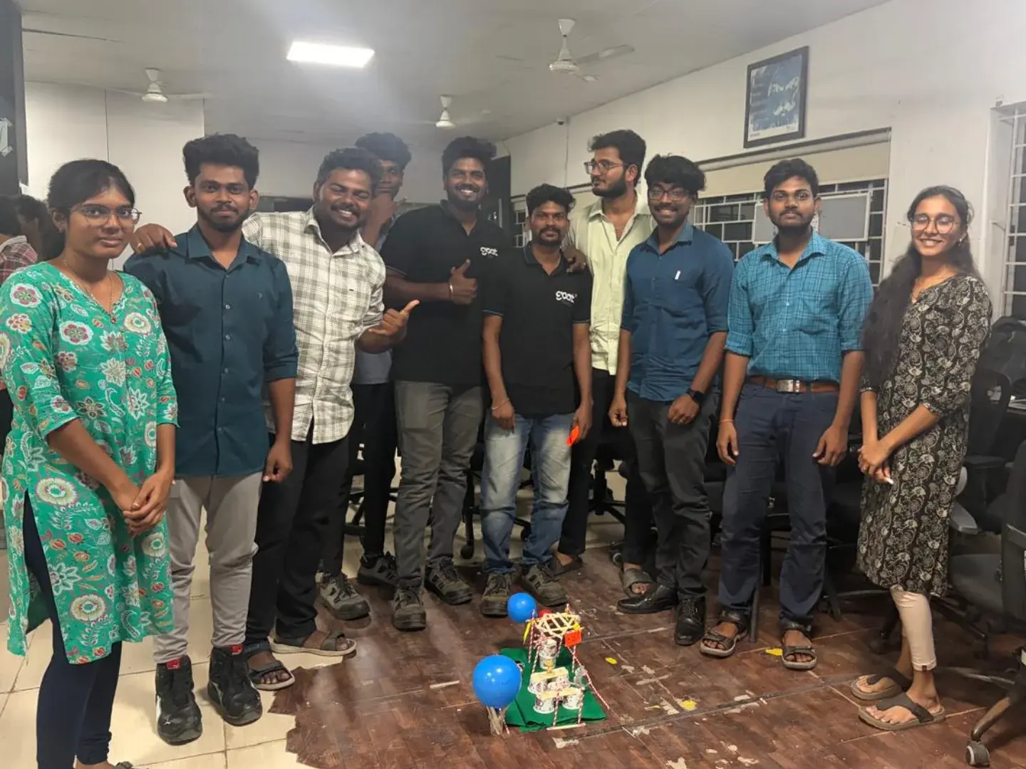 Team celebrating in the office with a robot model